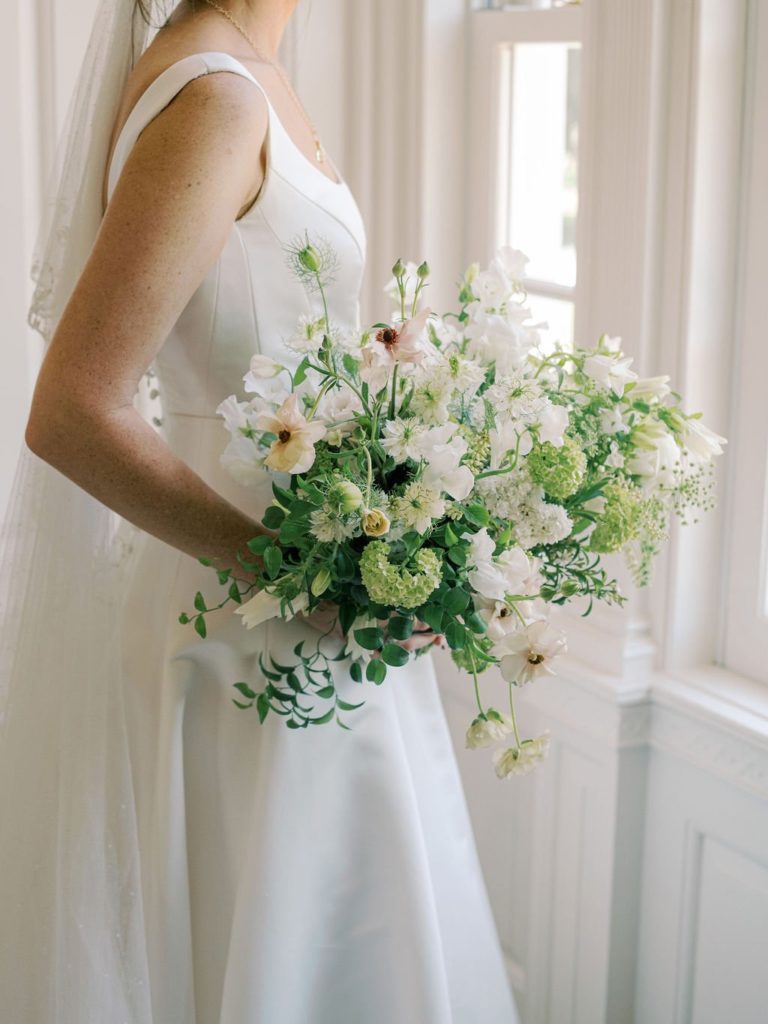 bride holding green and white garden style bouquet designed by floral designer Sophie Felts