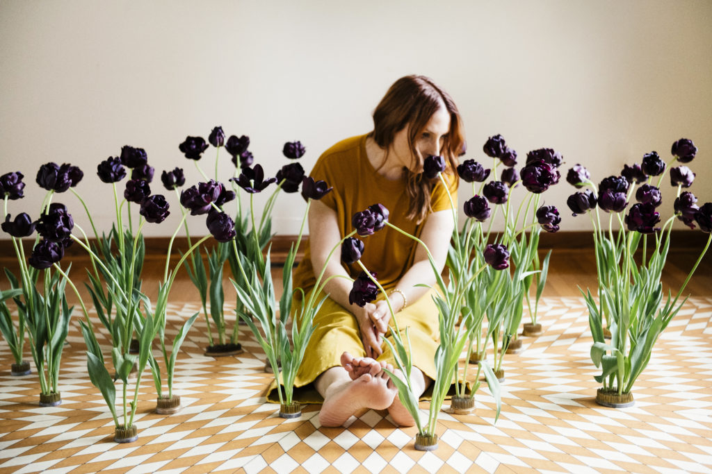 Florist Sue McLeary sitting on the floor surrounded by deep purple tulips