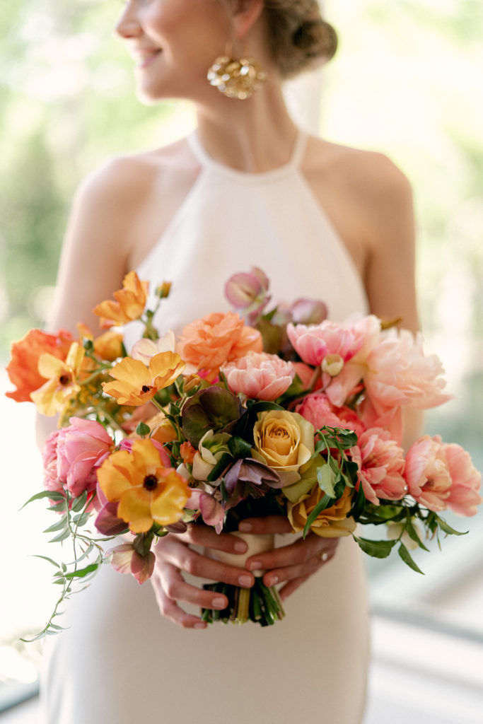 bride holding peach and yellow garden style bouquet designed by floral designer Sophie Felts