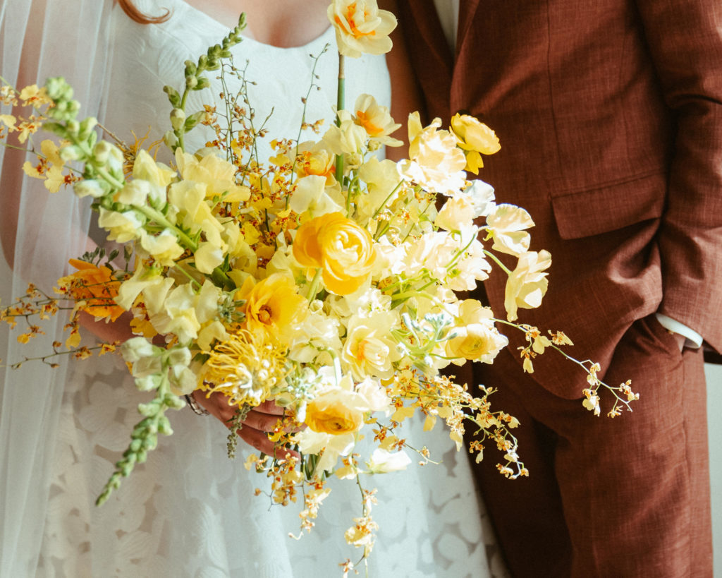 Bride holding a yellow bridal bouquet designed by Anthousai
