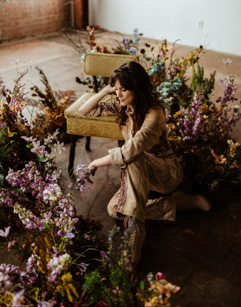 Hannah Lowery sits on the floor of her Edges Wild Studio surrounded by flowers