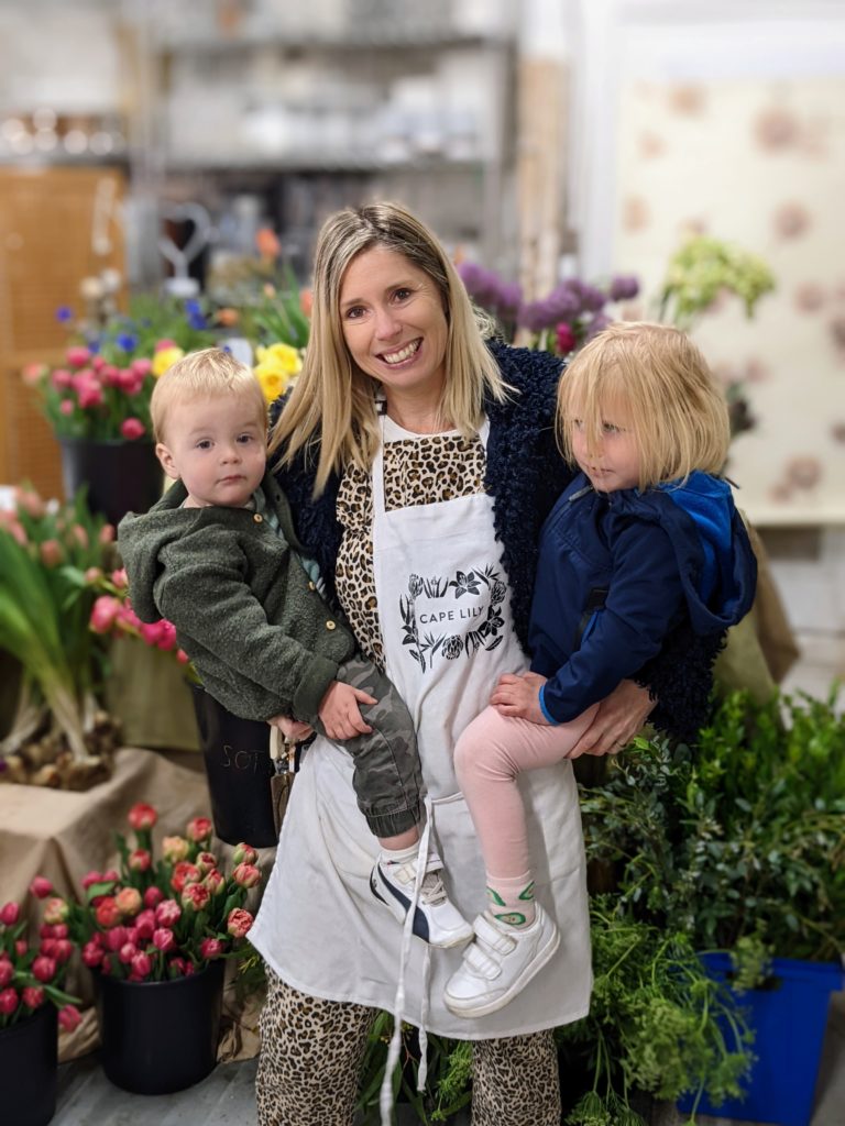 Sylvia Lukach, owner of Cape Lily, holding her children in her flower studio