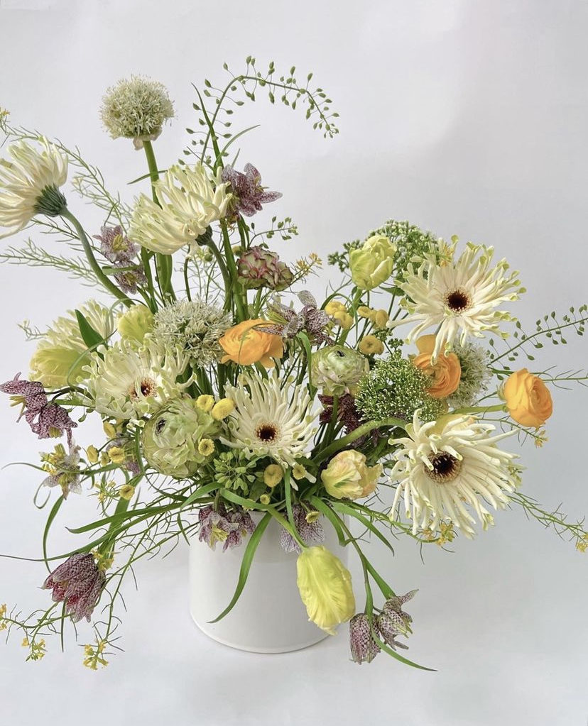 Flower arrangement by Popupflorist of yellow and cream flowers in a white vase