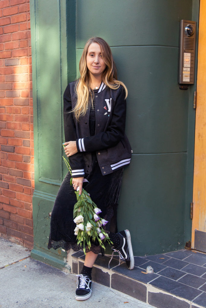 Popupflorist Kelsie Hayes stands outside a building in NYC holding a bouquet of white flowers