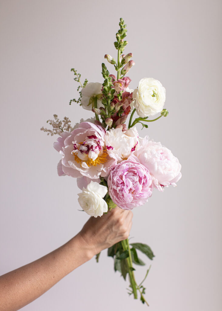 A hand holding a bouquet of wholesale flowers.