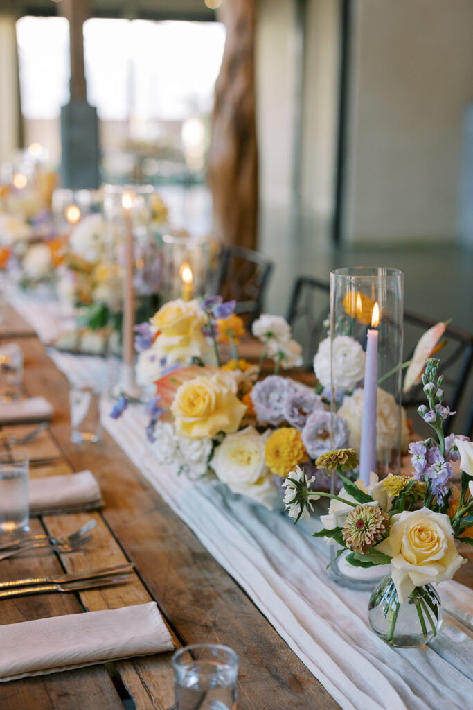 Floral centerpieces and pillar candles on a reception table designed by Abby Daigle and Stems of Austin