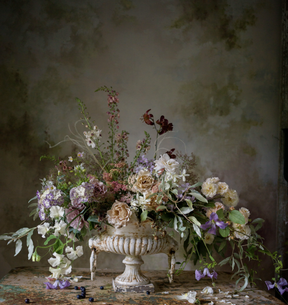 Vintage urn arrangement of draping garden flowers designed by creative designer Lucy Hunter in shades of lavender and cream