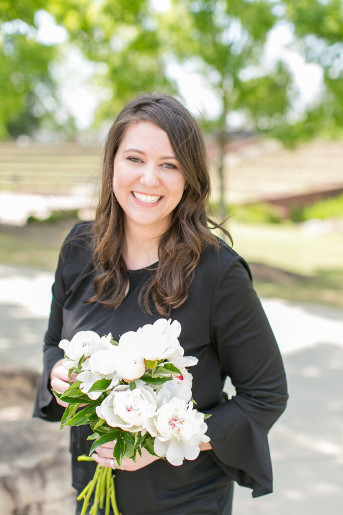 Retail flower shop owner Anna Stouffer of Urban Petals standing outside holding a bouquet of white flowers