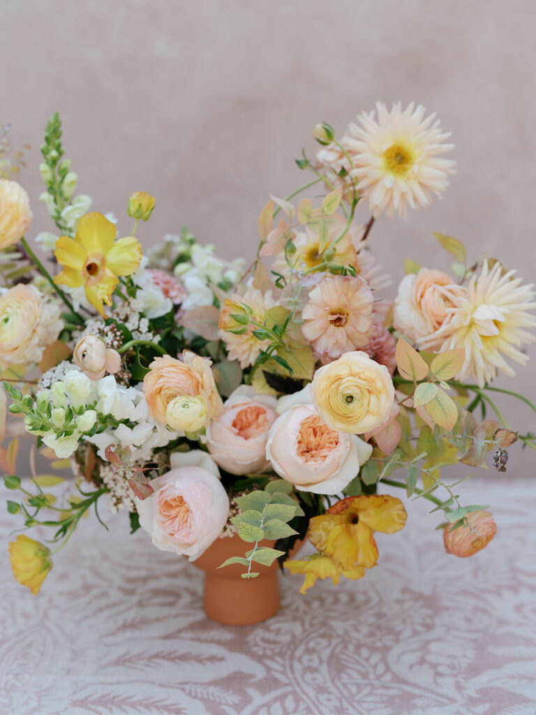 Peach floral arrangement designed by floral creative Jen Lagedrost Cavender sitting on a damask table linen