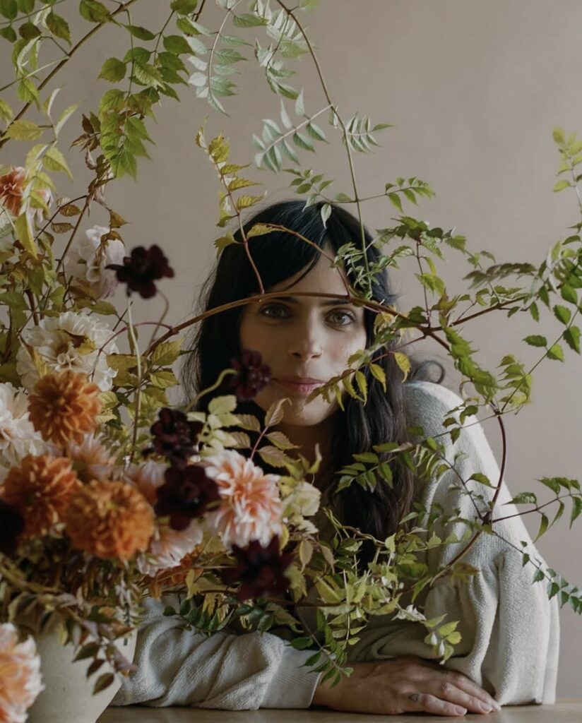 Wedding florist Rachael Lunghi of Siren Floral Co peeks through one of her floral arrangements